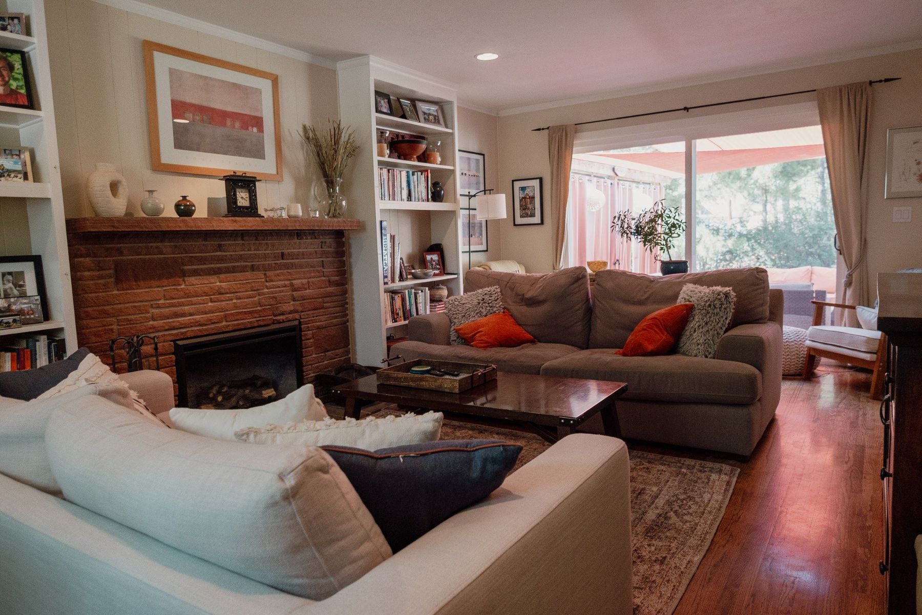 Warm living room with fireplace, bookshelves, and natural light