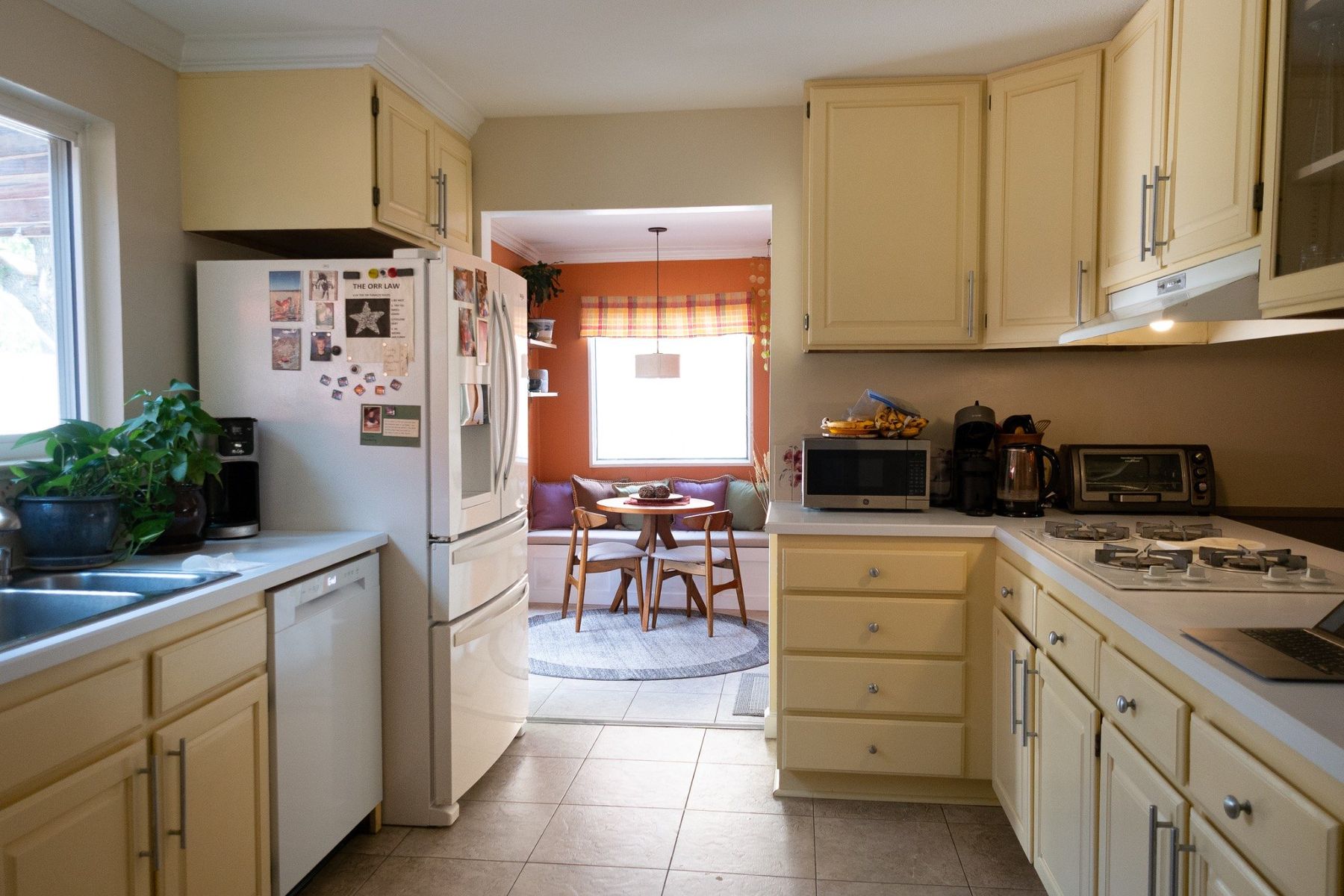 Bright residential kitchen opening into an orange breakfast nook