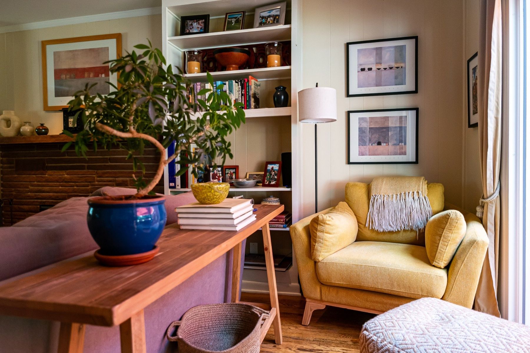 Reading corner with a yellow chair, artwork, and built-in shelves